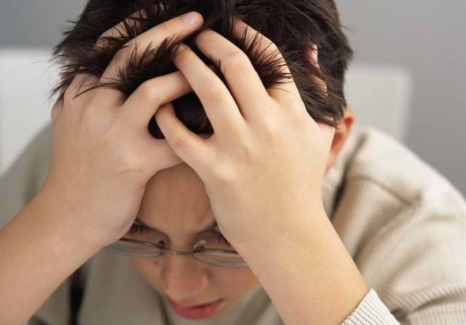 bé trai đeo kính ôm đầu