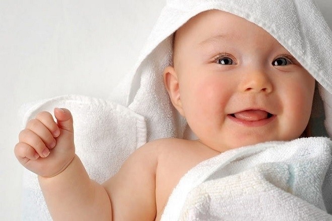 trẻ 3 tháng tuổi quấn khăn và nằm mỉm cười