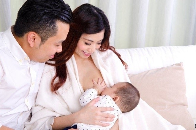bé 3 tháng tuổi bú sữa trong vòng tay bố mẹ