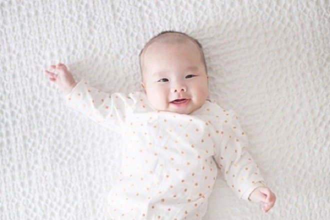 trẻ 4 tháng nằm chơi trên giường