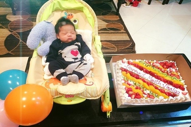 bé trai nằm trong ghế bên bánh đầy tháng