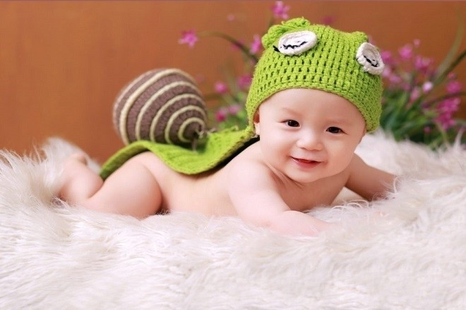 bé trai 1 tuổi nằm chơi trên chăn