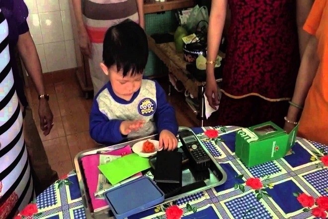 bé trai chọn đồ vật trong lễ thôi nôi