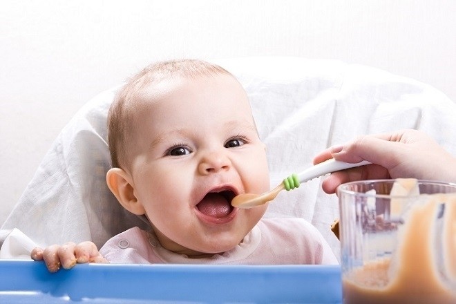 trẻ 4 tháng đang được mẹ đút cháo ăn dặm