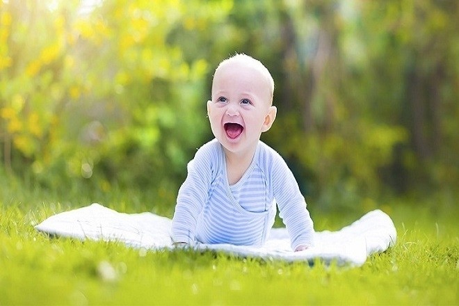 trẻ sơ sinh nằm phơi nắng trên cỏ