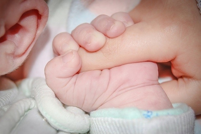 bé sơ sinh cầm chặt tay mẹ