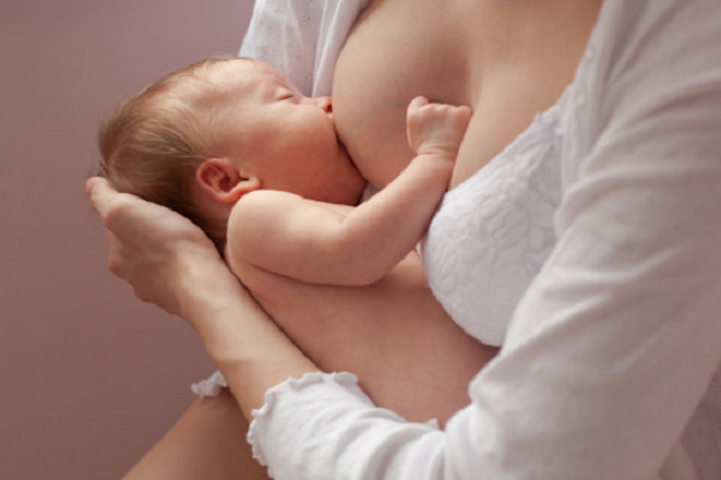 bé vịn tay vào ngực mẹ để bú sữa