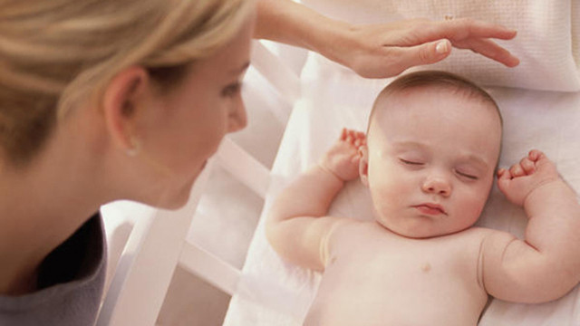 mẹ xoa đầu cho bé đang ngủ