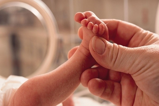 mẹ cầm chân trẻ sơ sinh
