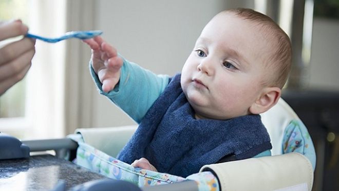 bé giơ tay vớ lấy muỗng ăn