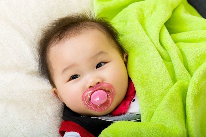 bé đang nằm ngậm núm vú giả