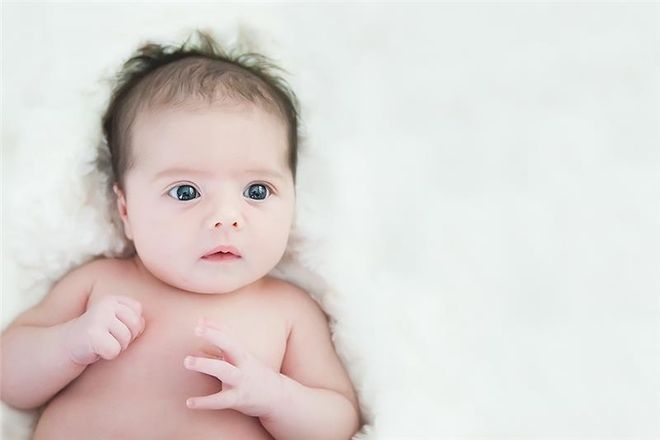 trẻ sơ sinh nằm trên nệm trắng
