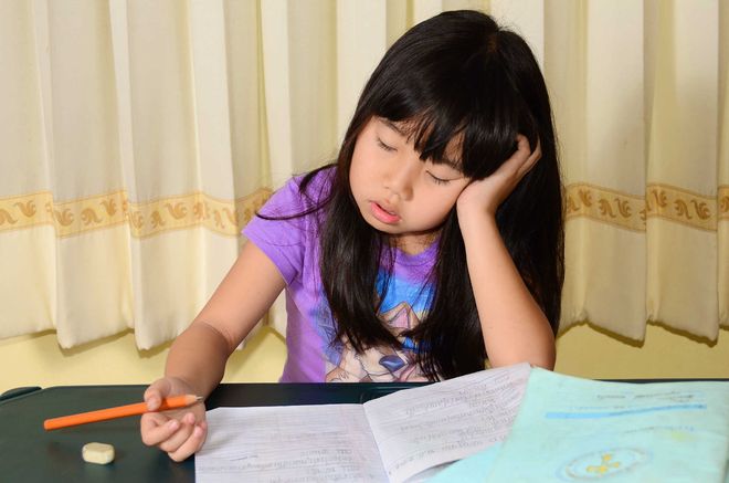 bé gái ngủ gật khi đang làm bài