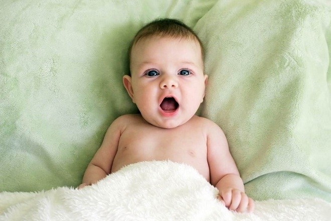 bé nằm trên nệm há miệng nói chuyện