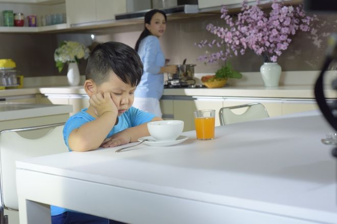 bé ngồi chống tay không chịu ăn