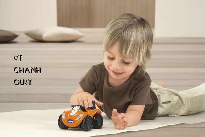 bé trai nằm chơi xe hơi trên sàn nhà