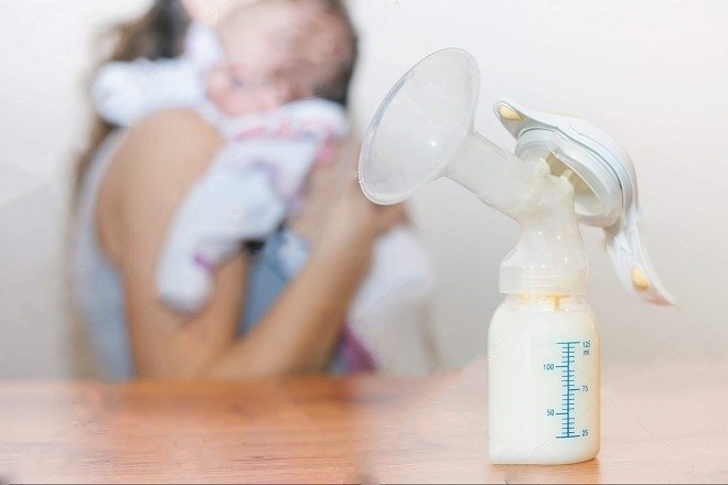 mẹ hút sữa đầy bình và ôm bé sơ sinh