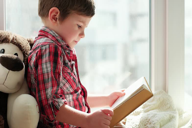 Bé ngồi đọc sách bên cửa sổ đủ ánh sáng