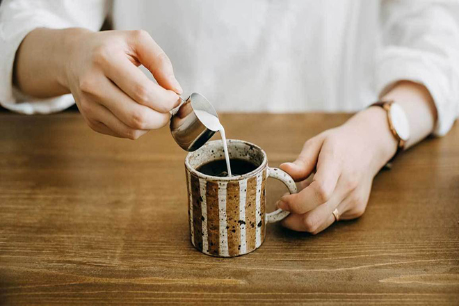 Người đàn ông pha sữa vào cà phê