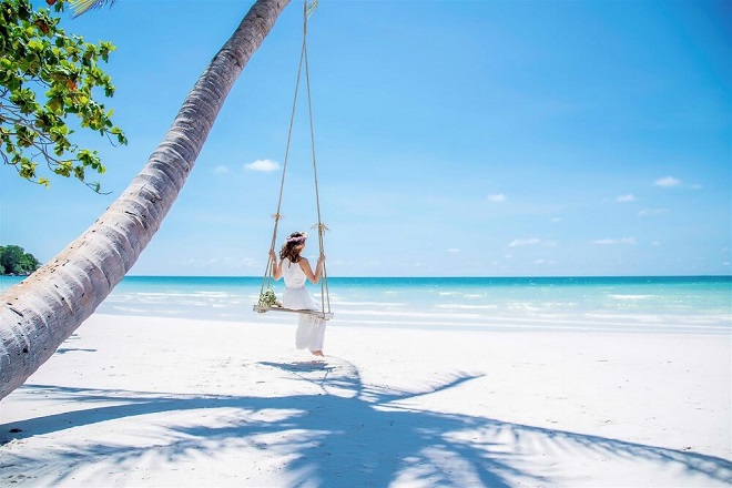 Cô gái váy trắng ngồi trên xích đu ở bãi biển