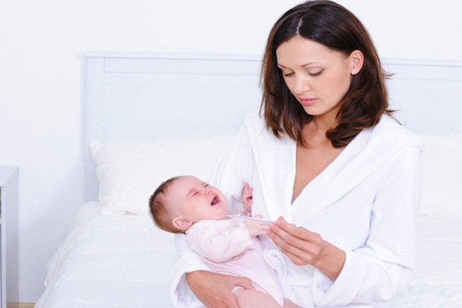 Mẹ bế bé và đo nhiệt độ
